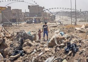 Children walk through the ruins of their neighborhood in Mosul